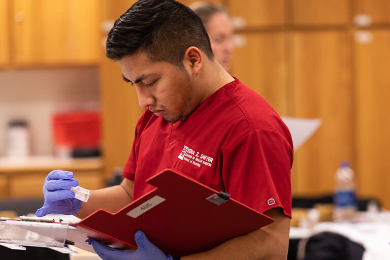 a student holding a vial and a folder of notes